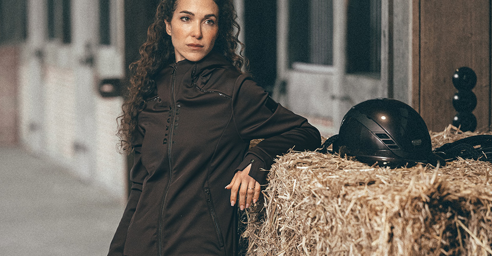 schwarzer Mantel, langer Schnitt, Stehkragen, Druckknöpfe, Reitbekleidung, schwarze Jacke, Stehkragen, Knopfleiste, Seitentaschen, Reithelm